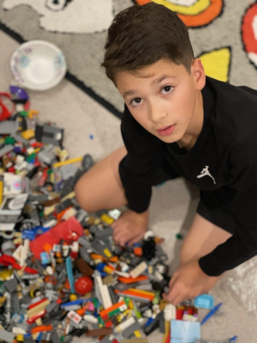 Noah sorting through LEGO bricks on the floor