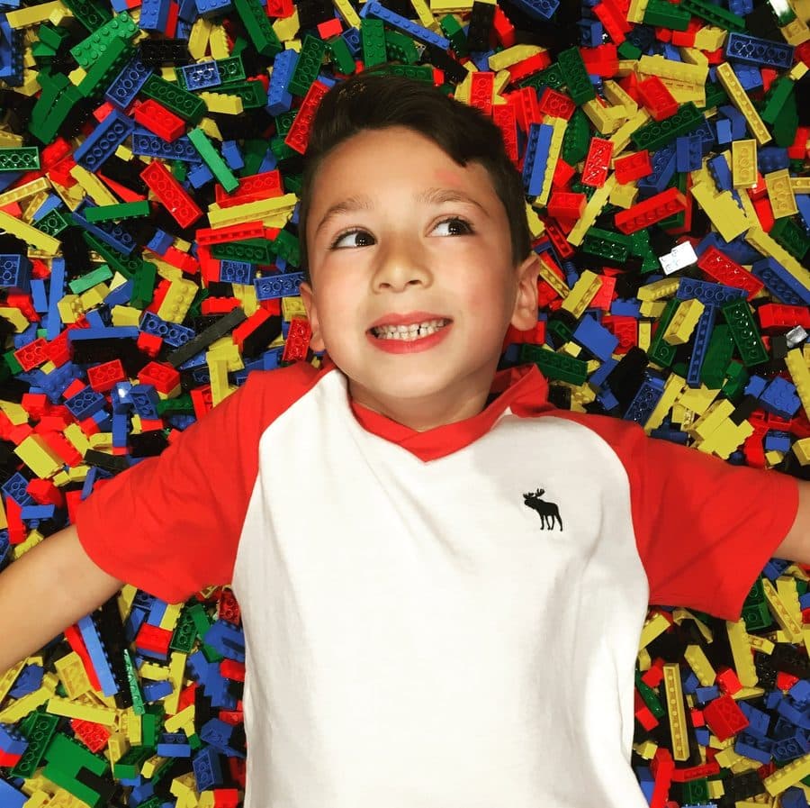 Noah as a young kid lying in a pile of LEGO bricks